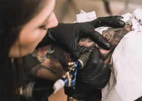 close up tattoo machine.  Woman creating picture on hand with it in salon photo