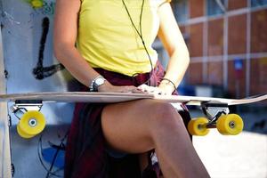 Beautiful hipster girl with skate board wearing sunglasses in the city. photo