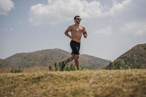 sporty man runner running on mountain plateau in summer photo