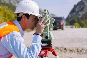 el ingeniero topógrafo está midiendo el nivel en el sitio de construcción. los topógrafos aseguran mediciones precisas antes de emprender grandes proyectos de construcción. foto