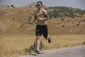 sporty man runner running on mountain plateau in summer photo