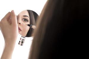 Portrait of a young woman applying liquid make up on her face. Isolated on white background photo