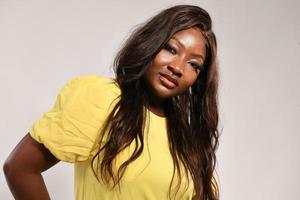 Happy Dark Skinned Woman in Yellow Fashion Dress. Beauty Afro American Model posing in studio isolated on gray background photo