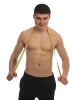 modelo masculino con gran cuerpo midiendo su cuerpo con cinta métrica foto