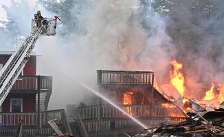 un solo bombero rocía un vapor directo en un edificio completamente incendiado foto