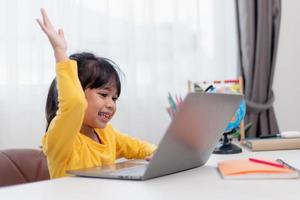 First day at school. Asian little girl using a laptop computer, studying through online e-learning system. photo
