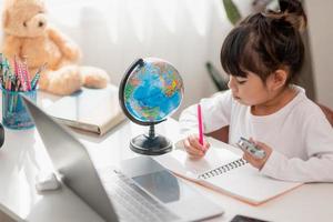 Asian little girl is learning the globe model, concept of save the world and learn through play activity for kid education at home. photo