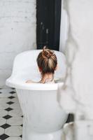 Young happy woman taking bath with foam at home, treat yourself photo