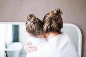 Young mother woman with long hair with little tween girl daughter in pajamas having fun in the morning at home, family spending time together in bathroom photo