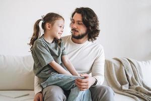 joven familia feliz con padre e hija en el sofá en la acogedora casa, día del padre foto