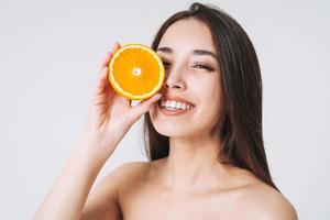retrato divertido de belleza de mujer asiática sonriente feliz con cabello largo oscuro con naranjas en las manos sobre fondo blanco aislado foto