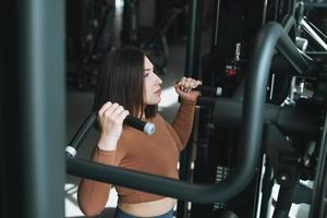 Joven mujer morena fitness entrenando para equipos de músculos de la espalda en el gimnasio foto