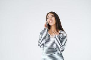 Young happy asian woman with long hair in striped longsleeve using mobile phone on white background isolated photo