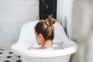 joven mujer feliz bañándose con espuma en casa, date un capricho foto