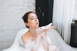 joven mujer feliz bañándose con espuma en casa, date un capricho foto