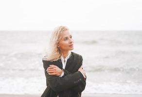 retrato de mujer rubia elegante en traje negro cerca del mar en una tormenta foto