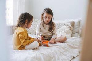 Cute dos niños niñas hermanas comiendo galletas en la cama en casa foto