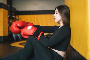 joven morena vestida de negro dedicada al entrenamiento de boxeo en el gimnasio del club de fitness foto