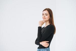 retrato de una joven y feliz mujer hermosa con cabello largo oscuro en manga larga negra y jeans en el fondo blanco aislado foto