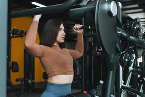 Young fitness brunette woman training for back muscles equipment at gym photo