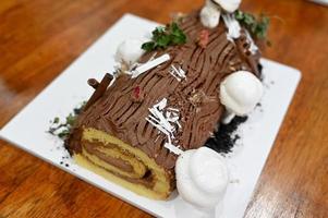 chocolate yule log pastel de navidad sobre fondo de madera foto