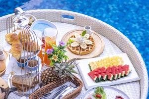 desayuno en piscina, desayuno flotante en villa resort. relajarse en el agua tranquila de la piscina, desayuno saludable y frutas tropicales. foto