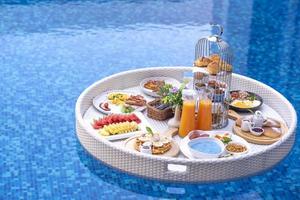 Breakfast in swimming pool, floating breakfast in villa resort. relaxing in calm pool water, healthy breakfast and tropical fruit. photo