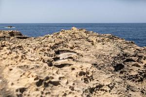 Texture of Volcanic rock surface in Cyprus look like moon surface. cliff, sea and sky background. selective focus photo