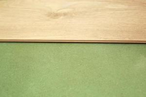 Installing wooden laminate or parquet floor in room over green base. assembling panels quickly and easily - affordable flooring. laying laminate flooring at home photo