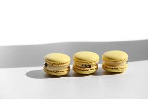 Set of yellow macaroons or macarons with shadow from window isolated on white background. Seamless pattern. Delicious healthy french dessert. Creative minimal modern concept. photo