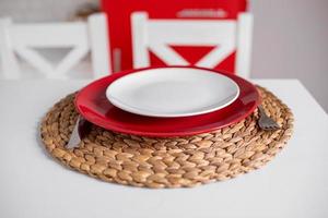 mesa para unas vacaciones románticas el día de san valentín, platos rojos y blancos con una vajilla de bambú sobre una mesa blanca. enfoque selectivo. foto