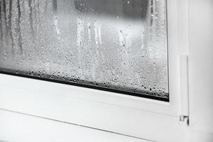 a plastic window with condensation of water on the glass. Double glazed PVC window. Concept defective plastic window with condensation, temperature difference, cooling, humidity in the room. photo