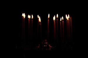 close up a lot of burning candles isolated on black background. photo