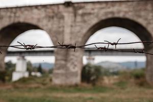 valla de púas en primer plano. en el fondo de un viaducto. foto