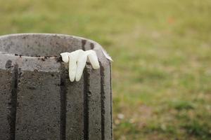 Used disposable glove on a garbage container close up. Disposal of personal protective equipment concept. selective focus photo