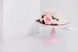 hermoso pastel de crema blanca decorado con velas de 2 años y rosas en estudio blanco. fiesta de cumpleaños - concepto de un año de nacimiento, fiesta, celebración de la vida y momentos memorables. foto