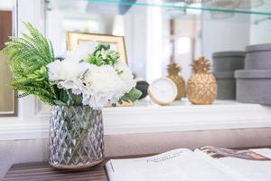 flor blanca con jarrón de cristal en la mesa de lectura foto