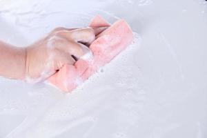 hombre lavando un auto blanco jabonoso con una esponja rosa foto