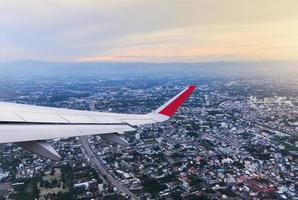 Wing of an airplane flying above the city photo