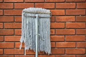 dirty mop against the orange brick wall 1 photo