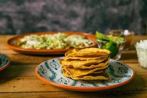 tostada de maíz, comida típica mexicana. tostadas en un plato sobre una mesa de madera.