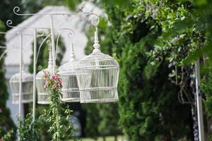 jaula de pájaros blancos como lámpara en el jardín foto