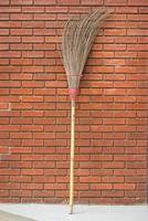 Straw broom against the orange brick wall