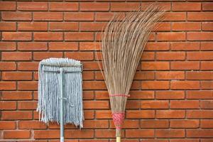 Straw broom with mop against the wall 2 photo