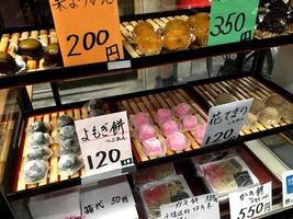 dulces mochi, postre japonés expuesto en un armario. colorido, invitando a los turistas a comprar para probar en pastelería en el mercado kuromon ichiba, osaka. foto