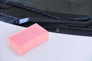 esponja rosa empapada en una superficie de coche foto