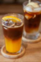Glass of americano mixed with orange juice blur background photo