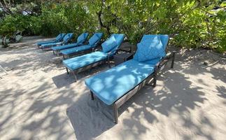 Lounge chairs or beach chairs on white sand beach in hot summer day in luxury tropical hotel photo