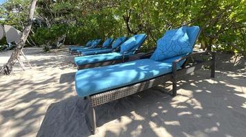 Lounge chairs or beach chairs on white sand beach in hot summer day in luxury tropical hotel photo