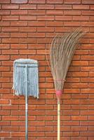Straw broom with mop against the wall 1 photo